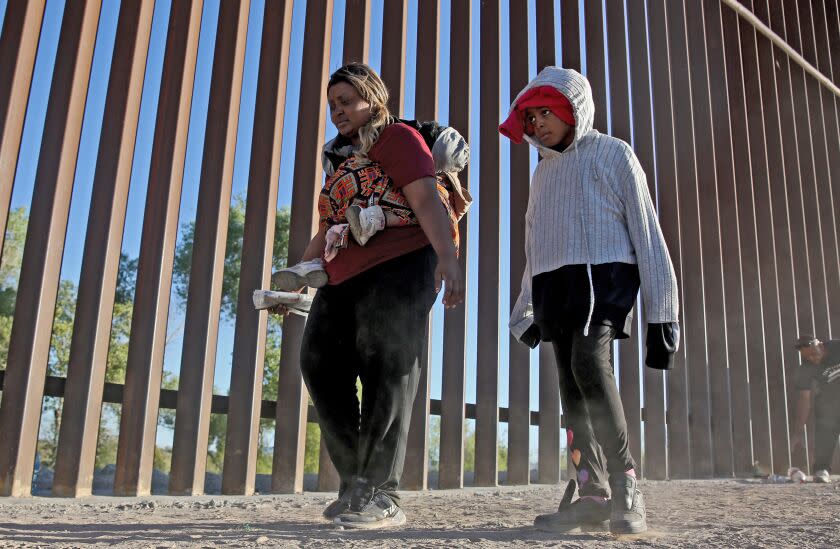 Nigerian Mary Otaiyi, 33, carries her four-year old daughter on her back as her 10-yr. old walks next to her along the border wall in Somerton, Arizona, on Friday, May 5, 2023. Otaiyi, who is seeking asylum in the United States, flew to Brazil where she took multiple buses through Bolivia, Peru and Central America before arriving at this location.