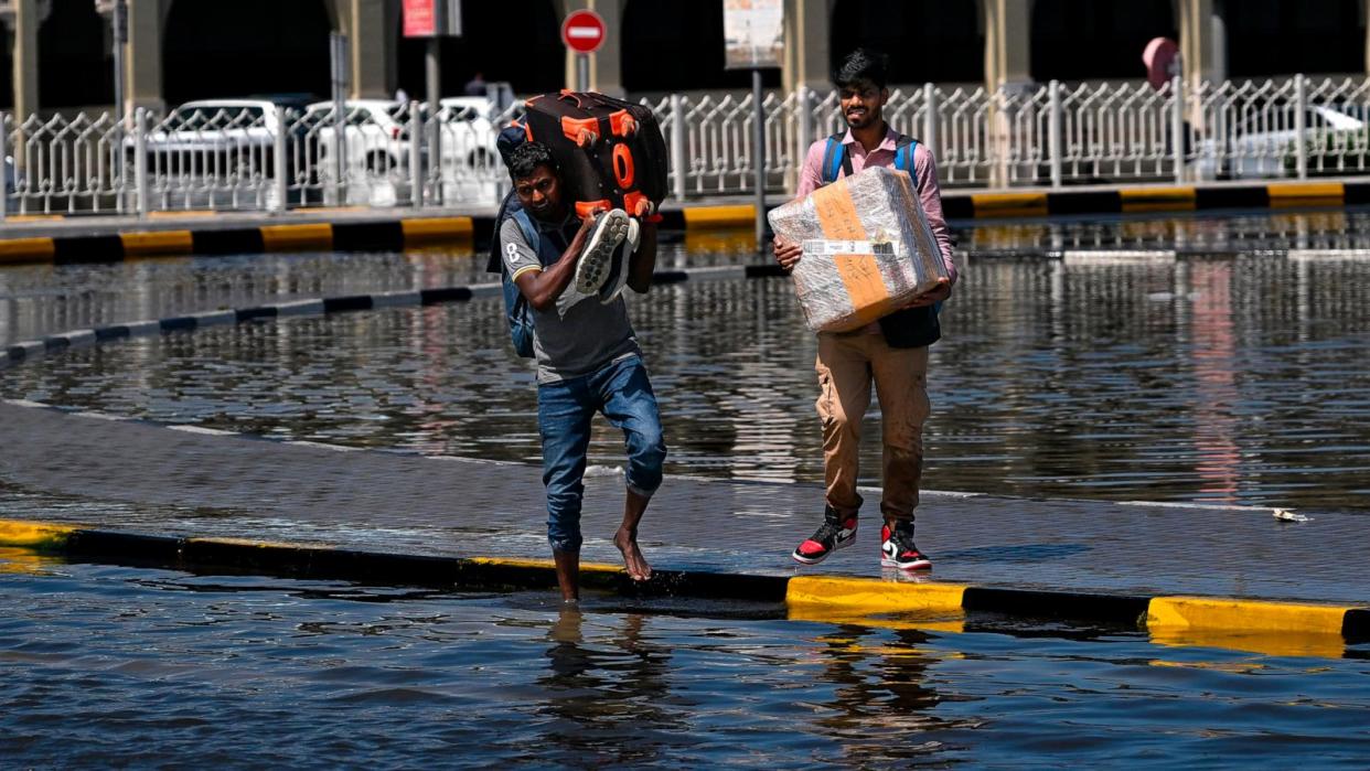 PHOTO: Men prepare to cross a flooded street following heavy rains in Sharjah on April 17, 2024.  (Ahmed Ramazan/AFP via Getty Images)
