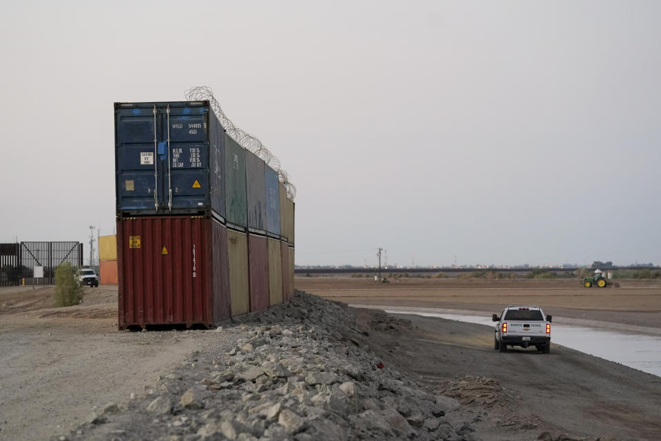 FILE - Border Patrol agents patrol along a line of shipping containers stacked near the border on Aug. 23, 2022, near Yuma, Ariz. The Cocopah Indian Tribe is welcoming the federal government's call for the state of Arizona to remove a series of double-stacked shipping containers placed along the U.S.-Mexico border near the desert city of Yuma, saying they are unauthorized and violate U.S. law. (AP Photo/Gregory Bull, File)