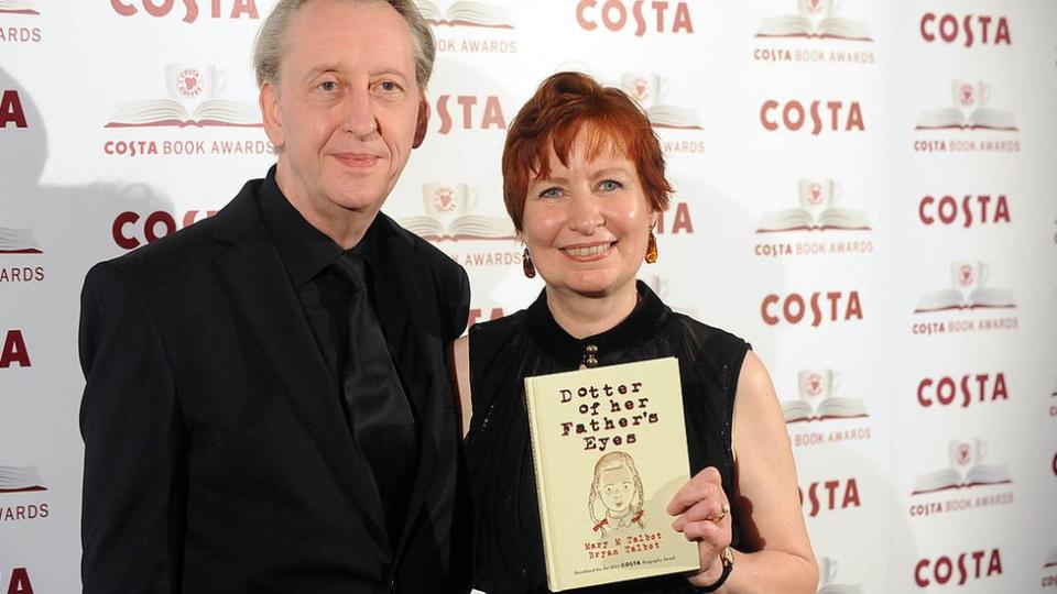 A man and a woman hold a book