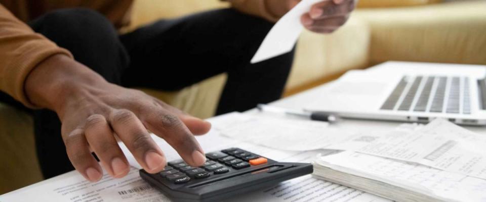 Close up of african American man calculating using machine managing household finances at home, focused biracial male make calculations on calculator paying bills, account taxes or expenses