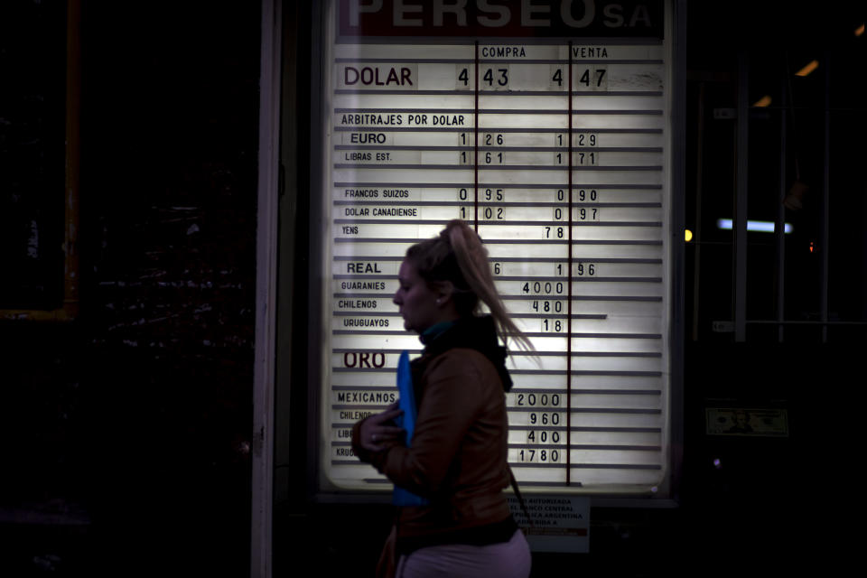 A woman passes a list of foreign currency exchange rates at an exchange house in Buenos Aires, Argentina, Wednesday, May 16, 2012. The AFIP tax collection agency's recent measure to control and approve every currency exchange operation in the country has made it practically impossible for Argentines to buy dollars, forcing them to get the currency on the black market. (AP Photo/Natacha Pisarenko)