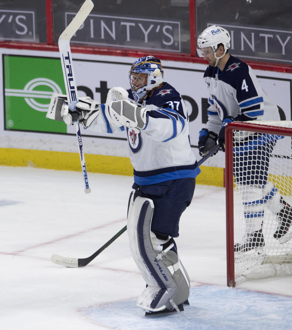 Winnipeg Jets goaltender Connor Hellebuyck celebrates as the buzzer sounds to end the team's NHL hockey game against the Ottawa Senators on Thursday, Jan. 21, 2021, in Ottawa, Ontario. (Adrian Wyld/The Canadian Press via AP)