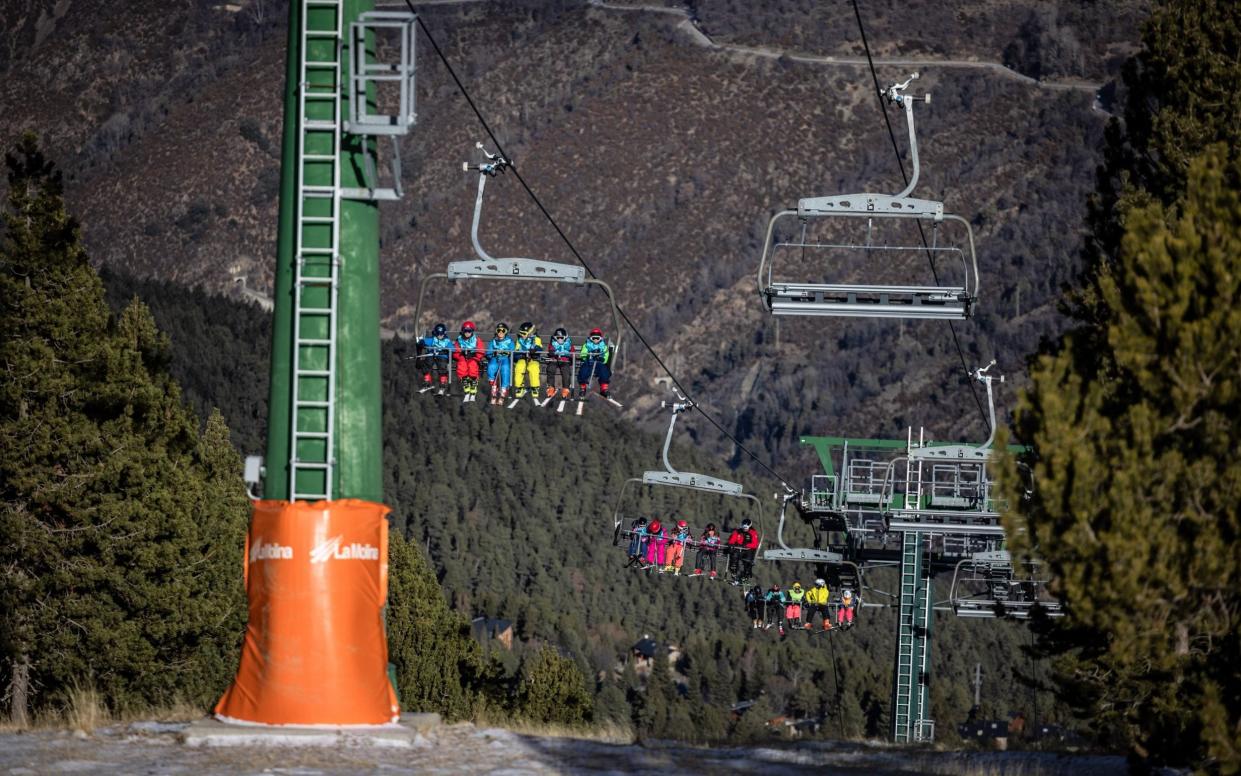 Skiers ride a lift over dry scrubland at La Molina ski resort in Girona, Spain