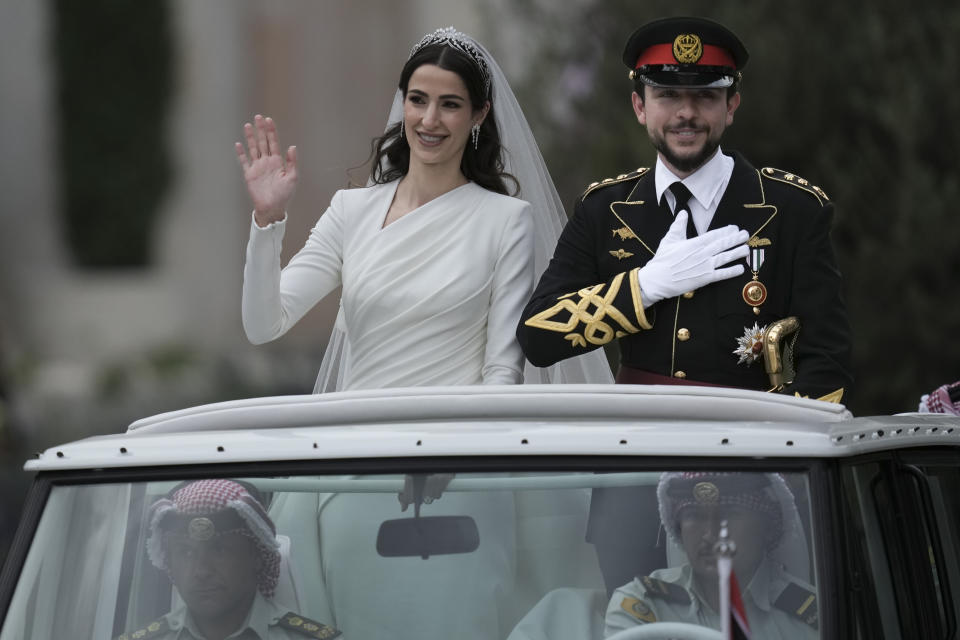 El príncipe heredero de Jordania, Hussein, y la arquitecta saudí Rajwa Alseif, saludan a la gente durante las ceremonias de su boda en Amán, Jordania, el jueves 1 de junio de 2023. (AP Foto/Nasser Nasser)