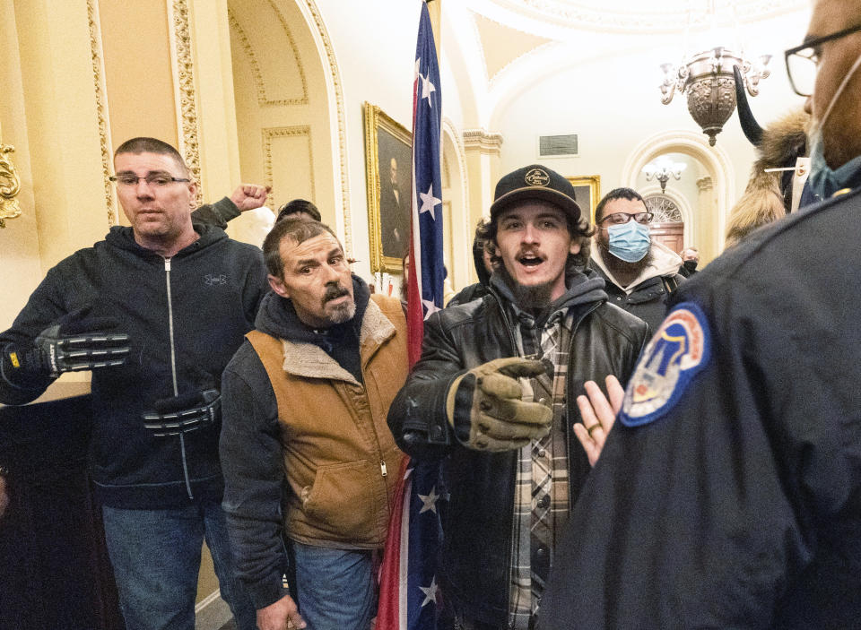 FILE - Violent protesters loyal to President Donald Trump, including Kevin Seefried, center, are confronted by U.S. Capitol Police officers outside the Senate Chamber inside the Capitol, Jan. 6, 2021 in Washington. Seefried, who threatened a Black police officer with a pole attached to a Confederate battle flag as he stormed the U.S. Capitol, has been sentenced to three years in prison. (AP Photo/Manuel Balce Ceneta, File)