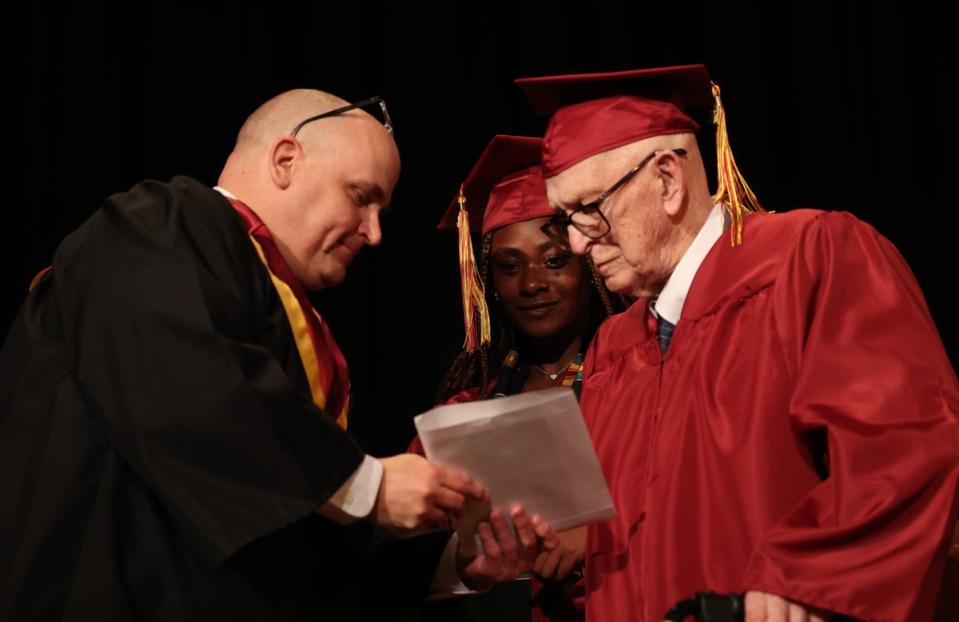 Harlan Olson, 101, accepts his diploma at Denfeld High School this month alongside senior Grace Nonnemacher (Duluth Public Schools)