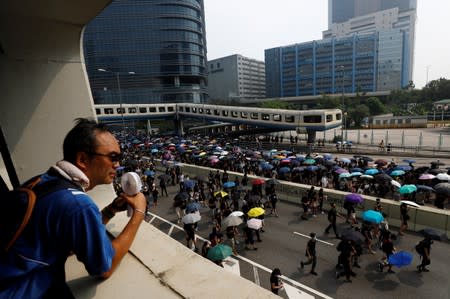 A man observes people marching during a protest in Hong Kong