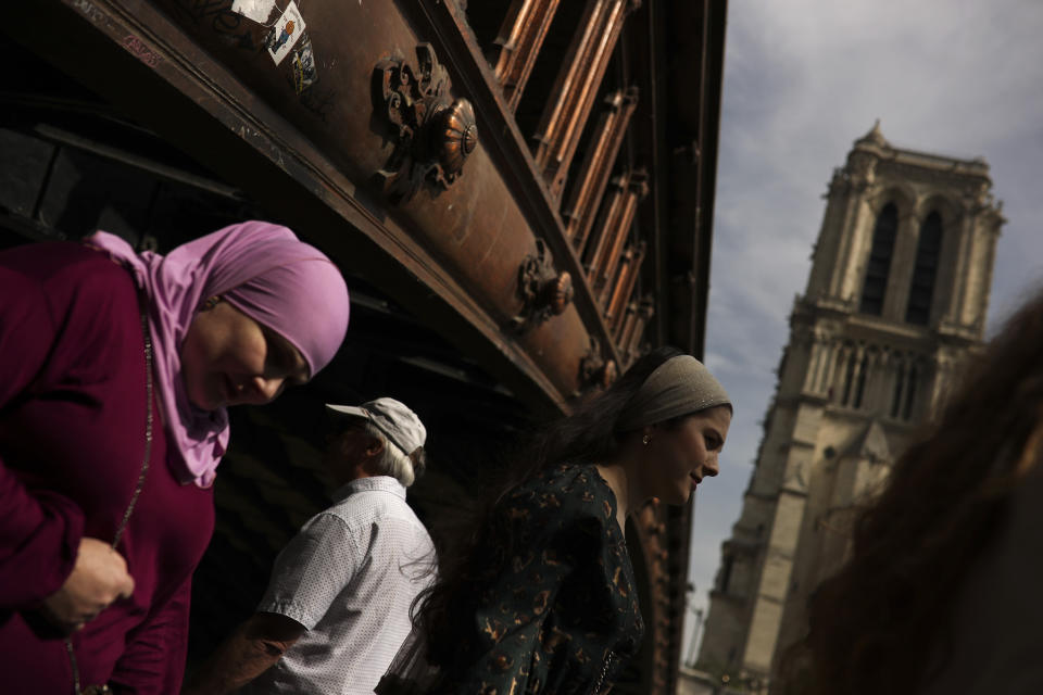 People walk past the Notre Dame cathedral in Paris, Monday, April 22, 2019. In the wake of the fire last week that gutted Notre Dame, questions are being raised about the state of thousands of other cathedrals, palaces and village spires that have turned France — as well as Italy, Britain and Spain — into open air museums of Western civilization. (AP Photo/Francisco Seco)