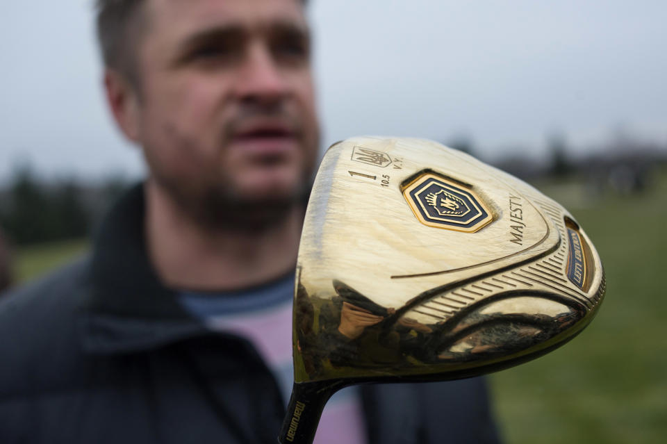 A man holds a golf club with the name of Ukrainian President Viktor Yanukovich on a golf course at the Ukrainian President Yanukovych's countryside residence in Mezhyhirya, Kiev's region, Ukraine, Saturday, Feb, 22, 2014. Viktor Yanukovych is not in his official residence of Mezhyhirya, which is about 20 kilometres north of the capital. Ukrainian security and volunteers from among Independence Square protesters have joined forces to protect the presidential countryside retreat from vandalism and looting.(AP Photo/Andrew Lubimov)