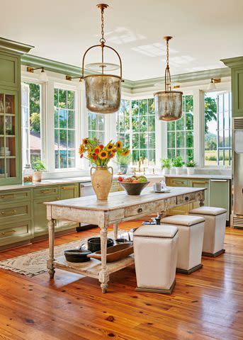 <p>Alison Gootee</p> Because the kitchen was a new addition, Caroline intentionally chose warm fixtures and finishes that add character, like unlacquered brass hardware and bell jar lanterns from Visual Comfort & Co. The cabinets are painted Farrow & Ball’s Treron (No. 292).