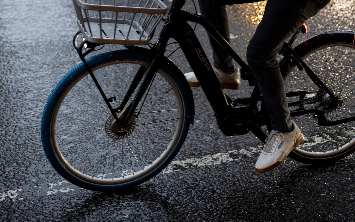 A cyclist pedals his e-Bike along Piccadilly on a rainy afternoon in Westminster, on 12th December 2023, in London, England