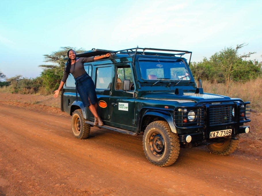 Woman smiling hanging off safari vehicle in Africa