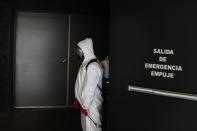 A worker waits for the end of a film to disinfect a theater following a movie screening, at the Cineteca Nacional, Mexico's film archive, in Mexico City, Wednesday, Aug. 12, 2020. After being closed for nearly five months amidst the ongoing coronavirus pandemic, movie theaters in the capital reopened Wednesday at 30% capacity. (AP Photo/Rebecca Blackwell)