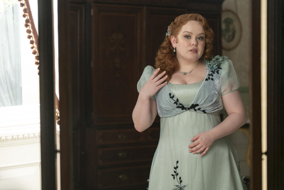 Penelope in an elegant historical dress with floral details, standing indoors