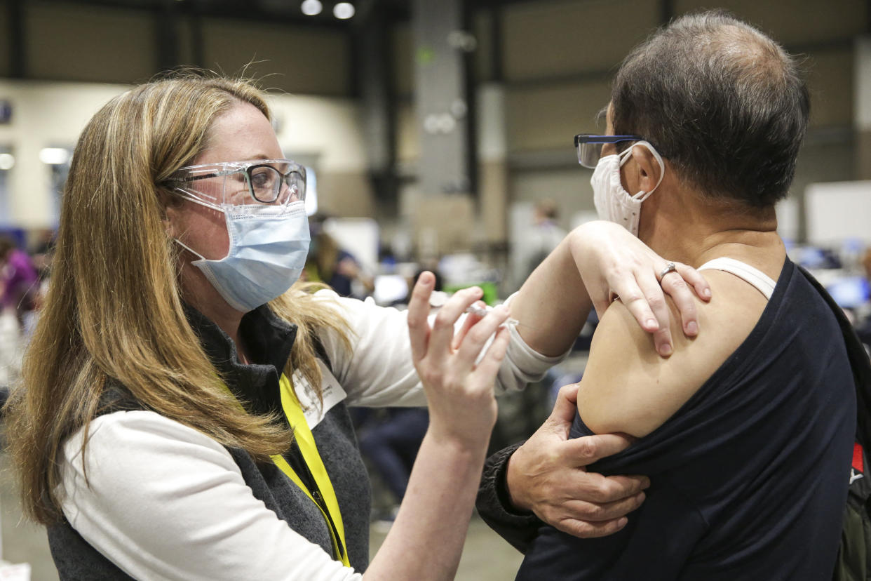 Nurse Jaime Navetta gives the Pfizer Covid-19 vaccine to Tianji Yu during opening day of the Community Vaccination Site, a collaboration between the City of Seattle, First & Goal Inc., and Swedish Health Services at the Lumen Field Event Center in Seattle, Washington on March 13, 2021. (Jason Redmond/AFP via Getty Images)