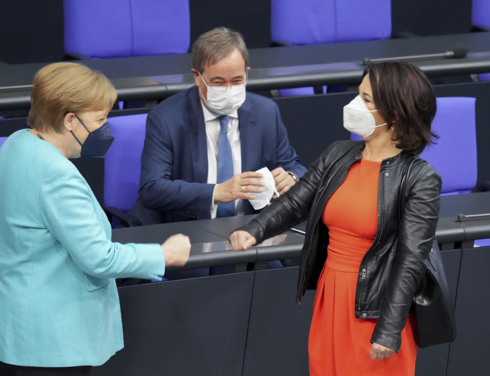 FILE - In this Thursday June 24, 2021 file photo,German Chancellor Angela Merkel, left, welcomes the top candidates for the upcoming national elections Annalena Baerbock, right, of the Green Party and Armin Laschet, center, of Christian Democratic Union's prior to a session of the German parliament Bundestag in Berlin, Germany. Climate change is among the top concerns for Germans going into this year's national election that will determine who replaces Angela Merkel as Chancellor. But while voters admit they are worried about the state of the planet, especially after last the deadly floods that hit Germany in July, many fear the cost of backing the environmentalist Green party that's campaigned strongest for meeting the Paris climate accord's goals. (Kay Nietfeld/dpa via AP, file)