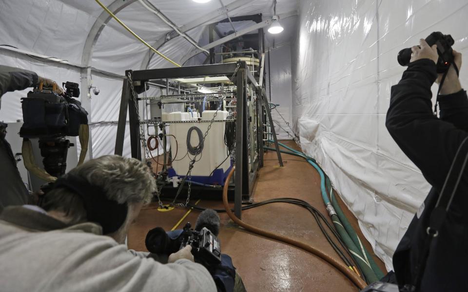 FILE - In this Thursday, Jan. 2, 2014, file photo, members of the media photograph one of two field deployable hydrolysis systems in a protective enclosure aboard the MV Cape Ray in Portsmouth, Va. The American ship MV Cape Ray is set to arrive Thursday, Feb. 13, 2014, at the naval base of Rota on Spain’s southwestern coast used by the U.S. to resupply ahead of an unprecedented mission to collect and destroy mustard gas, raw materials for sarin nerve gas and tons of other highly toxic chemicals that form part of Syria’s chemical weapons program. (AP Photo/Steve Helber, File)