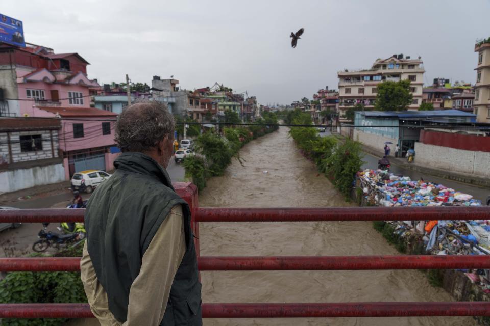 Un hombre mira al río Bagmati, crecido por las lluvias del monzón, en Katmandú, Nepal, el miércoles 27 de julio de 2022. Un comité gubernamental que se creó para ayudar a limpiar el río estudia construir represas río arriba donde el agua de lluvia pueda capturarse y almacenarse durante la temporada del monzón y ser liberada durante los meses secos para descargar el río y mover los desechos río abajo desde Katmandú. (AP Foto/Niranjan Shrestha)