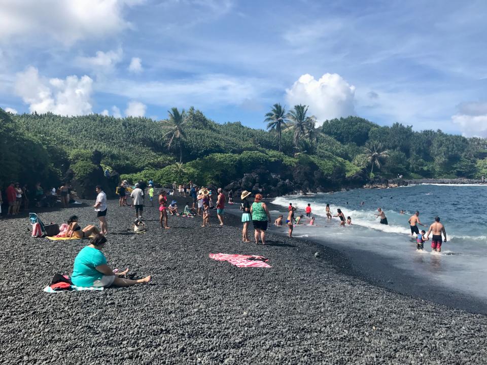 poeple on black sand beach at Waiʻānapanapa State Park. Maui, Hawaii