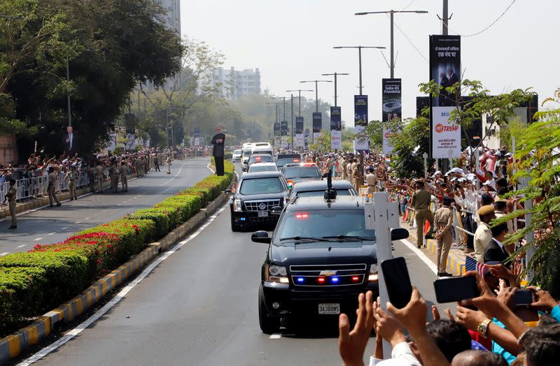 People wave as a motorcade transporting U.S. President Donald Trump and first lady Melania Trump passes enroute to Gandhi Ashram in Ahmedabad