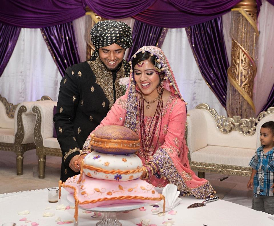 This July 2013 photo provided by Lynn Barsigian Photography shows Ateeb Ansari and Sheema Aleem cutting the cake at their wedding. Ansari’s family hosted the couple’s wedding reception at the Owego Treadway Inn & Conference Center in New York because the venue allows outside catering. The Muslim family needed to use a caterer that could provide halal meat to serve to their guests. (AP Photo/Lynn Barsigian Photography)