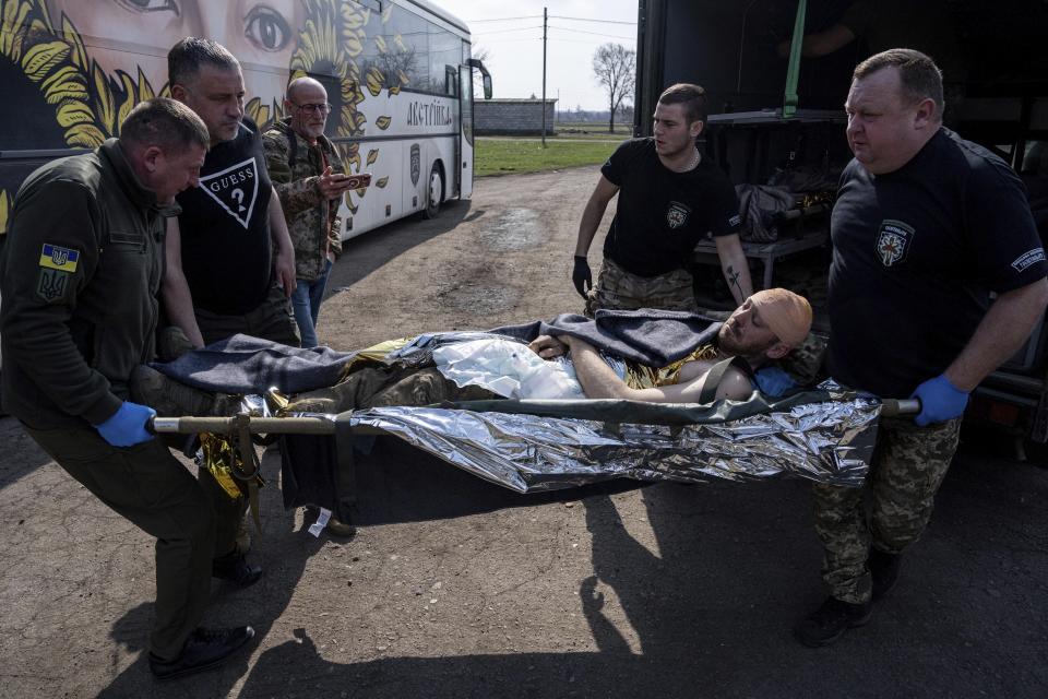 Volunteers from the Hospitallers paramedic organisation transport an injured Ukrainian soldier into the special medical bus during evacuation in Donetsk region, Ukraine, Wednesday, March 22, 2023. (AP Photo/Evgeniy Maloletka)