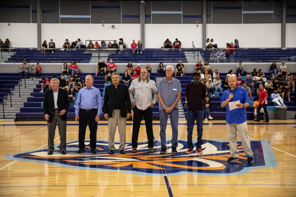 The 1973 Carroll high school basketball team is honored during a game at Carroll's new campus on Friday, Dec. 9, 2022, in Corpus Christi, Texas. The team from left, coach Mike Kunstadt, point guard Glenn Rollins, shooting guard Danny Kaspar, forward Preston Bailess, center Steve Frontz, and guard forward Nellie Kelly Jr., stand in the middle of the arena during halftime.