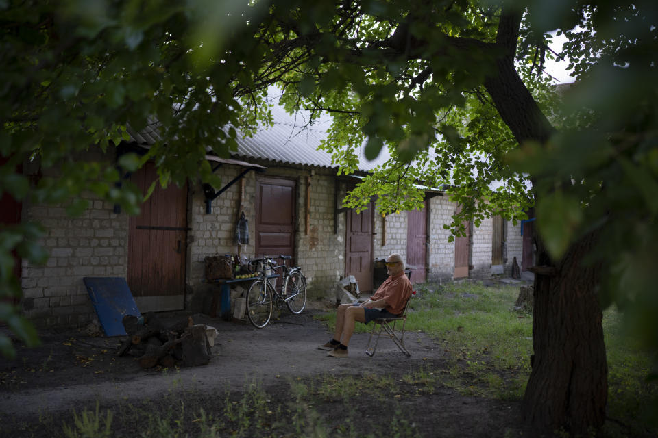 A man sits outside his home in Kupiansk-Vuzlovyi, Ukraine, Wednesday, Aug. 23, 2023. Residents close to the northeast frontline are ignoring calls from Ukrainian authorities to evacuate as the fighting inches closer. (AP Photo/Bram Janssen)