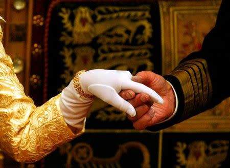 The hand of Britain's Queen Elizabeth II (L) is held by her husband, Prince Philip, Duke of Edinburgh, after her speech at the State Opening of Parliament in the House of Lords in London, November 13, 2002. REUTERS/Russell Boyce/Files