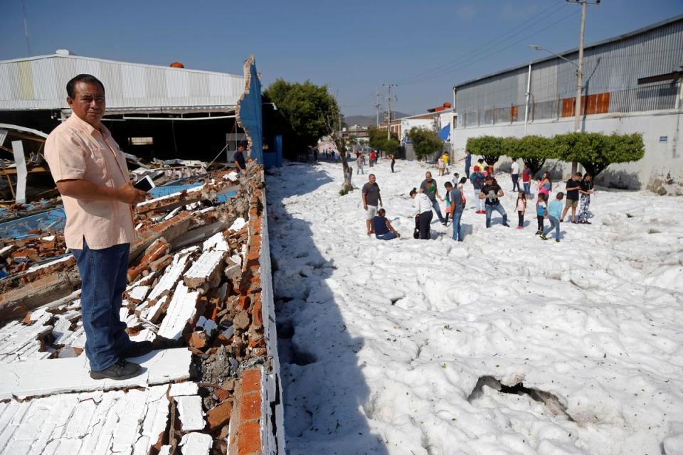 墨西哥第二大城在夏天被冰雹風暴襲擊，當地民眾站在積雪中。（東方IC）