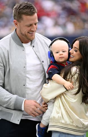 <p>Logan Riely/Getty</p> Former Houston Texans player J.J. Watt looks on while his wife, Kealia Ohai Watt, holds their son, Koa Watt