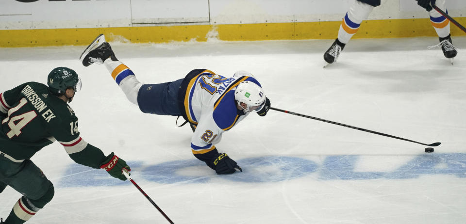 St. Louis Blues' Tyler Bozak (21) falls while trying to maintain control of the puck as Minnesota Wild's Joel Eriksson Ek (14) pursues during the third period of Game 2 of an NHL hockey Stanley Cup first-round playoff series Wednesday, May 4, 2022, in St. Paul, Minn. The Wild won 6-2. (AP Photo/Jim Mone)