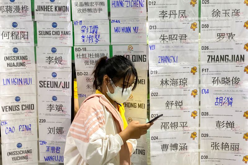 A woman wearing a protective mask is seen at a counter arranging transport for Chinese tourists arriving at Bangkok’s Don Mueang Airport