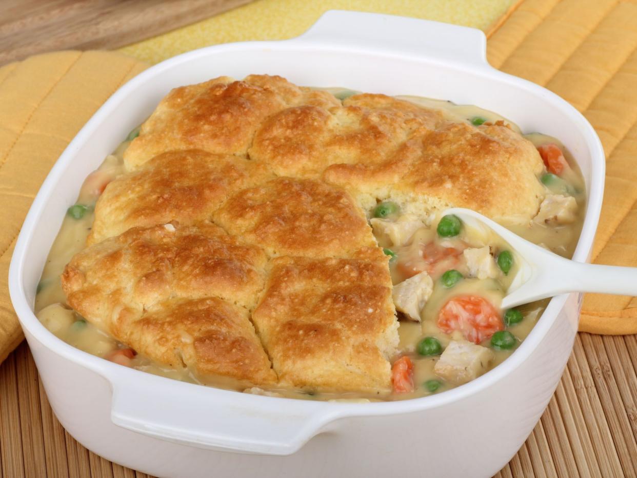 Chicken pot pie with carrots and peas in white ceramic serving dish