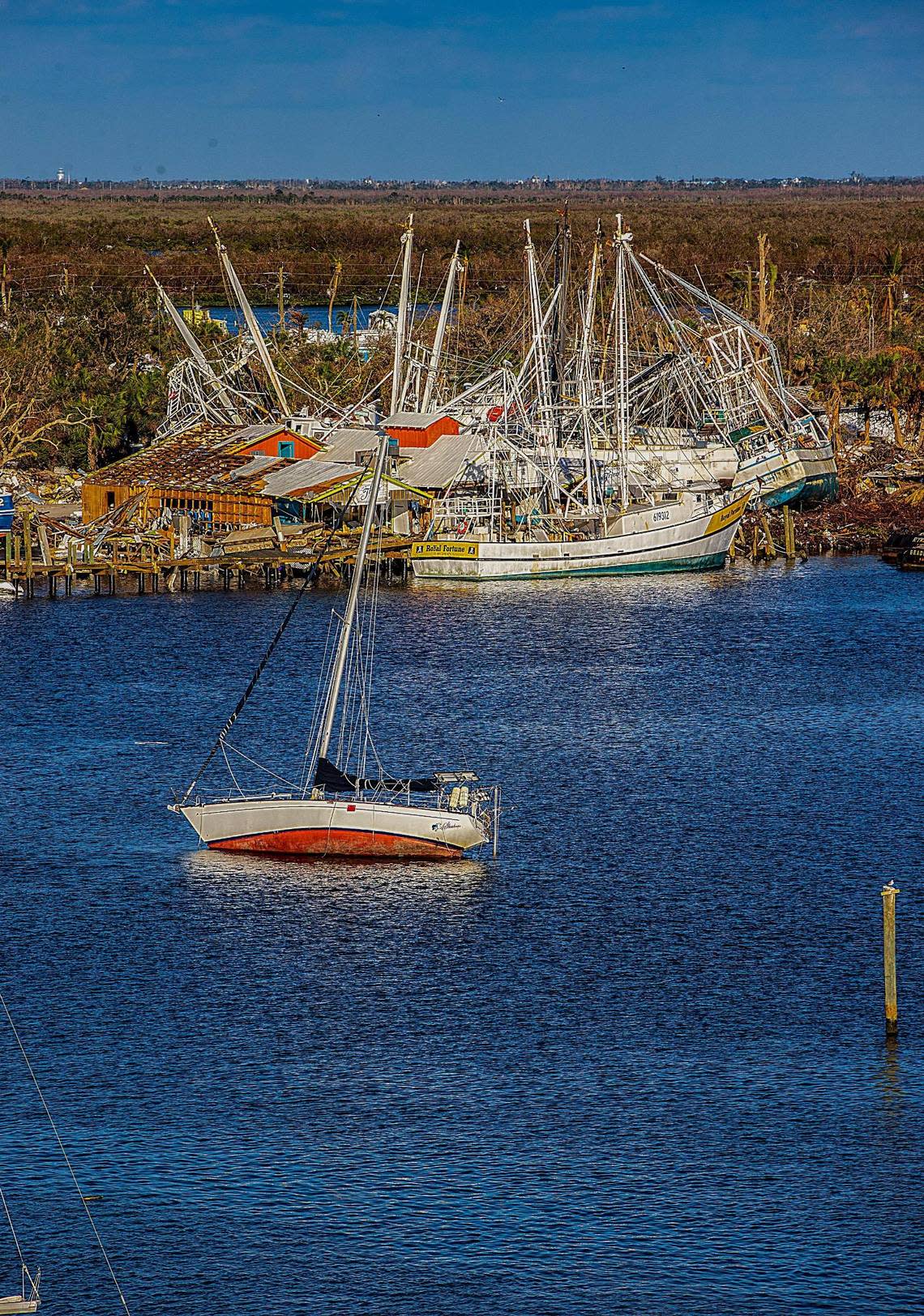 A sailboat lists to its side in Matanzas Harbor in Fort Myers Beach in front of a mass of wrecked shrimping boats Wednesday, Oct. 26, 2022. The damage was caused by Hurricane Ian, with hit the area as a Category 4 storm Wednesday, Sept. 28, 2022.