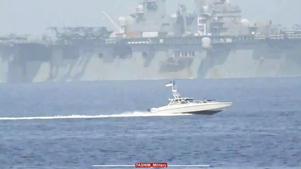 In this image provided by the Iranian Revolutionary Guard via Tasnim News agency on Sunday, Aug. 20, 2023, a Revolutionary Guard speedboat moves near USS Bataan at the Strait of Hormuz, in the mouth of the Persian Gulf. (Iranian Revolutionary Guard/Tasnim News Agency via AP)