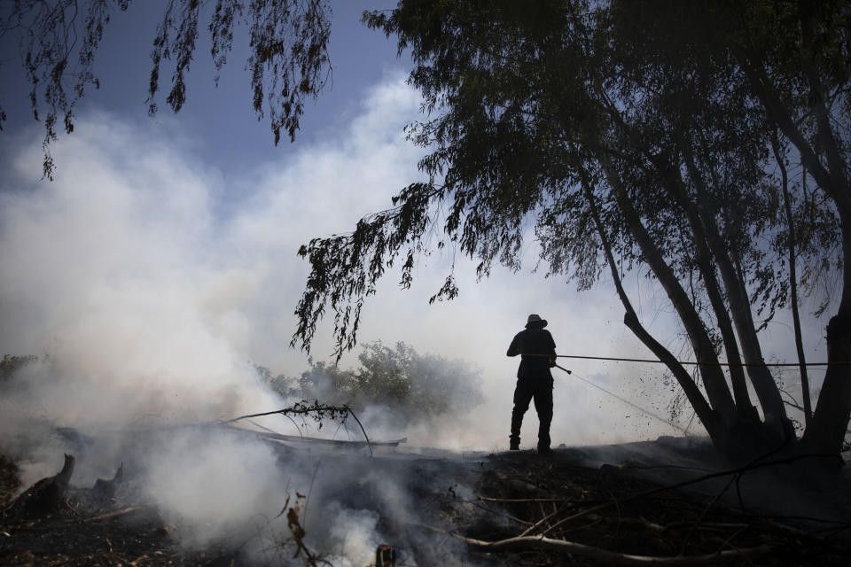 A volunteer attempts to extinguish a fire started by an incendiary device launched from the Gaza Strip, on the Israeli side of the border between Israel and Gaza, Monday, Aug. 24, 2020. Militants affiliated with Hamas have launched scores of incendiary balloons into southern Israel in recent weeks in a bid to pressure Israel to ease the blockade imposed since Hamas took control of the territory in 2007. (AP Photo/Ariel Schalit)