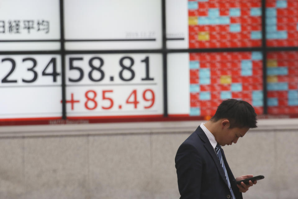 A man stands in front of an electronic stock board of a securities firm in Tokyo, Wednesday, Nov. 27, 2019. Shares were mostly higher in Asia on Wednesday after a fresh set of record highs on Wall Street, spurred by encouraging signs on trade talks between the U.S. and China. (AP Photo/Koji Sasahara)