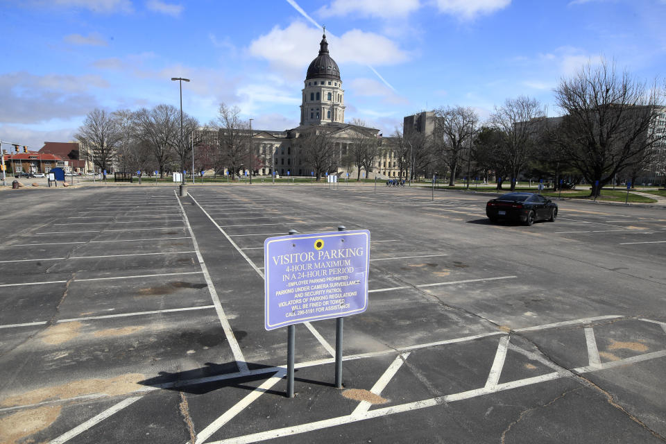 Empty parking spaces surround the Kansas Statehouse In Topeka, Kan., Wednesday, March 25, 2020. The Statehouse is closed to visitors. Shawnee County issued a stay-at-home order beginning tomorrow. (AP Photo/Orlin Wagner)