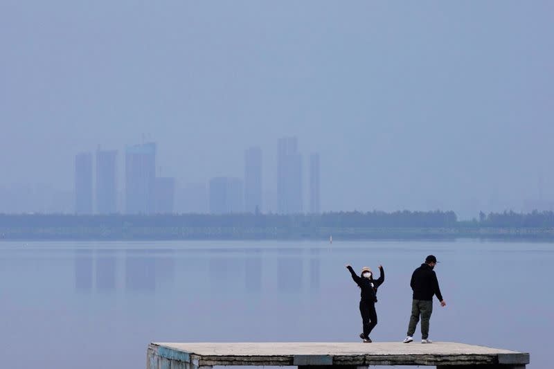 FILE PHOTO: Woman wearing a face mask dances on the East Lake in Wuhan