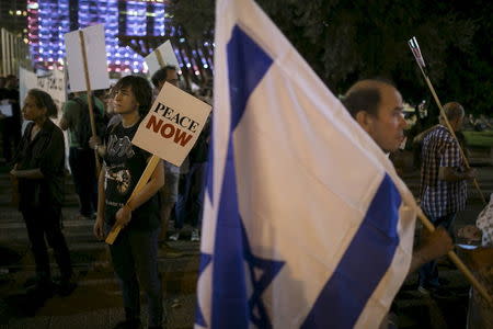 Left-wing protesters, one holding a placard bearing the logo of Peace Now, an Israeli NGO that tracks and opposes Jewish settlement in the occupied West Bank and East Jerusalem, take part in a rally in Tel Aviv, in this October 24, 2015 file picture. REUTERS/Baz Ratner/Files