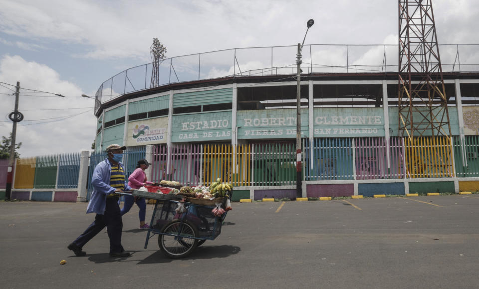 Los vendedores ambulantes llevan su fruta para vender afuera del estadio de béisbol Roberto Clemente en Masaya, Nicaragua, el jueves 28 de mayo de 2020. A medida que el nuevo coronavirus se extendió y las economías se cerraron en América Latina, Nicaragua permaneció abierta -escuelas, tiendas, salas de conciertos y estadios de béisbol- operando ininterrumpidamente por orden del gobierno pese a la pandemia del nuevo coronavirus. (AP Foto/Alfredo Zuniga)