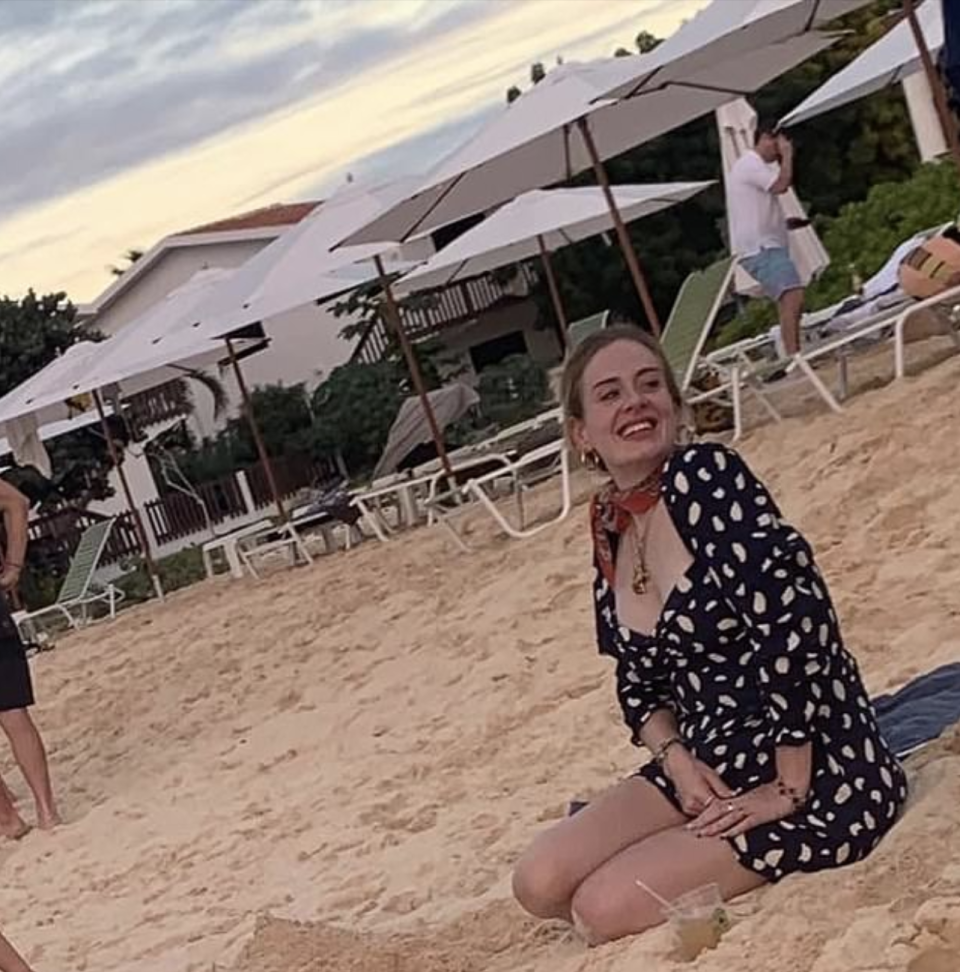 Adele in a black and white long sleeved dress on a beach in the Caribbean