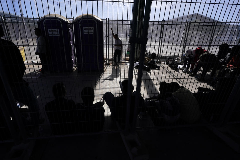 FILE- Men wait in a holding area on Dec. 15, 2023, at a Border Patrol station in Ajo, Ariz. U.S. asylum officers were instructed nearly a year ago to apply a higher screening standard on people who cross the border illegally to claim asylum after passing through another country. But they are too understaffed to have much impact. (AP Photo/Gregory Bull, File)