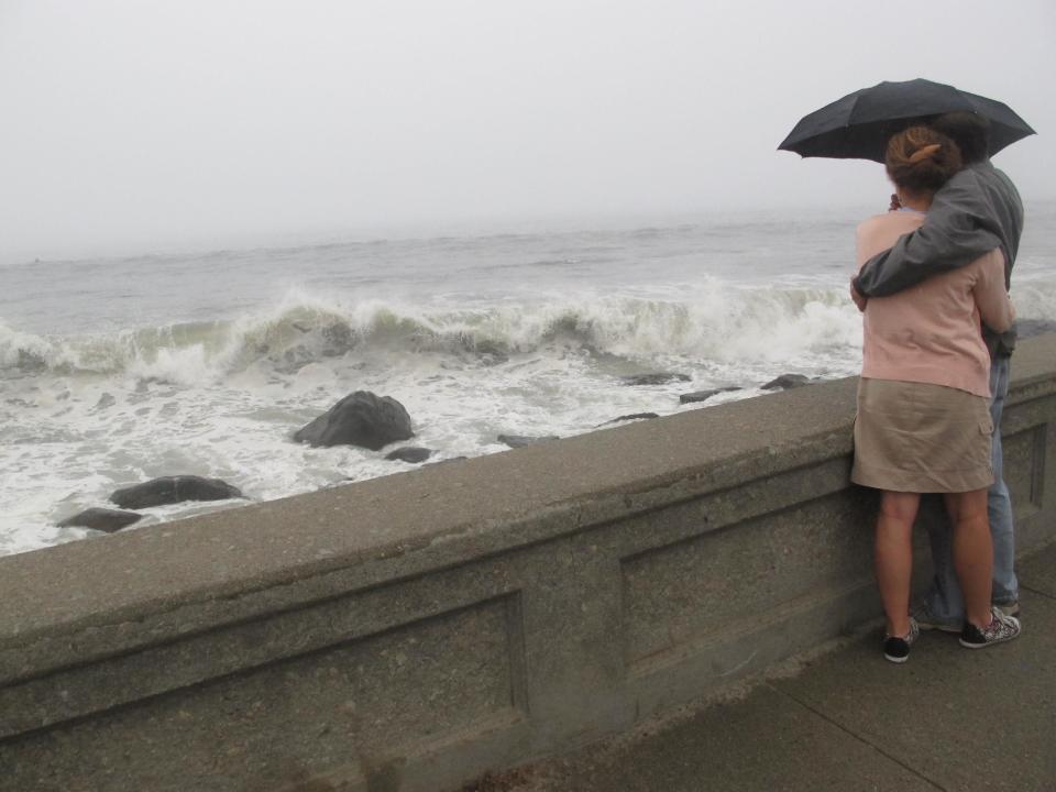 In this Aug. 27, 2011 photo, Sarah Pease-Kerr and Chris Barrett of South Kingstown, R.I., watch waves from Hurricane Irene crash onto the shore on in Narragansett, R.I. (AP Photo/David Klepper)