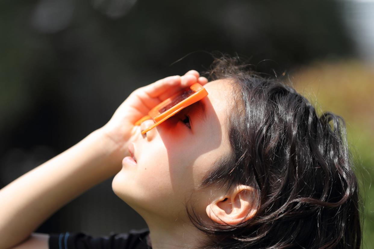A child uses solar eclipse glasses.