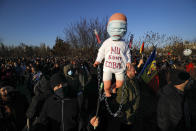 Anti-vaccination protesters hold a doll with "I don't want to be a lab rat" written on it during a rally outside the parliament building in Bucharest, Romania, Sunday, March 7, 2021. Some thousands of anti-vaccination protestors from across Romania converged outside the parliament building protesting against government pandemic control measures as authorities announced new restrictions amid a rise of COVID-19 infections. (AP Photo/Vadim Ghirda)