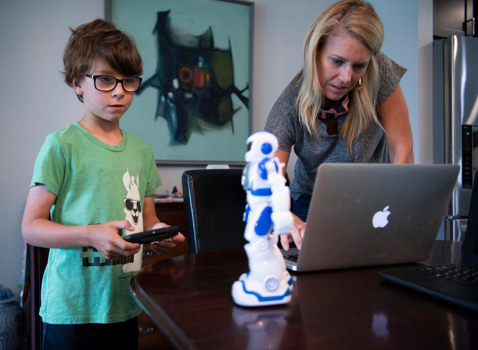 Heather Powell works to connect her son, Hawkes, to a lesson on her laptop from their home on the first day of school Aug. 4 in Nashville.