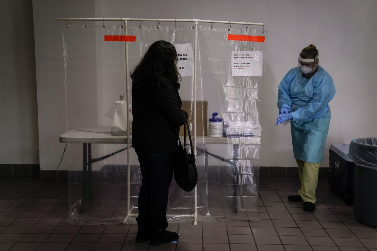 Nurse Leslie Clark puts on a new pair of protective gloves to collect a nasal swab sample at a COVID-19 testing site in Los Angeles on Dec. 27, 2020. 